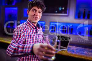 Portrait of smiling man holding beer glass at bar counter