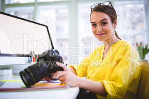 Portrait of confident female professional with camera at editing