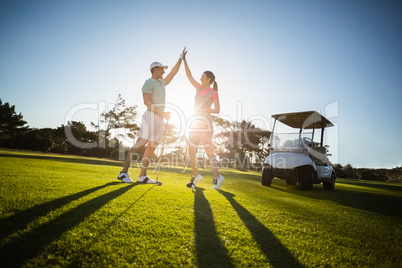 Happy golf player couple giving high five