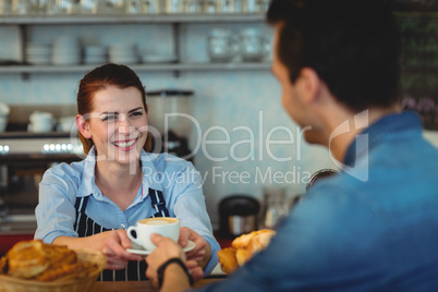 Cheerful barista giving coffee to customer at cafeteria