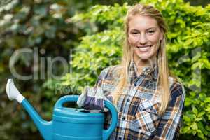 Confident female gardener holding watering can