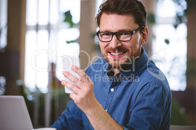 Portrait of confident businessman using mobile phone at office