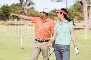 Smiling golfer man pointing while standing by woman
