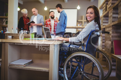 Confident disabled businesswoman using laptop in office