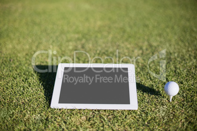 Close-up of golf ball on tee by digital tablet