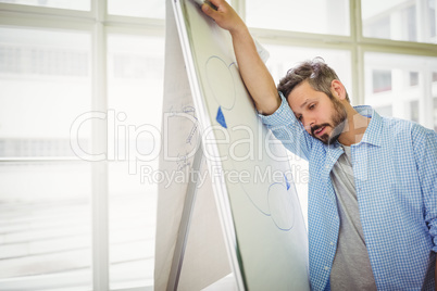 Tired businessman leaning on whiteboard in office