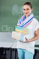 Portrait of teacher holding books in classroom