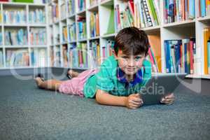 Portrait of boy using digital tablet in school library