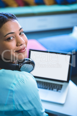 Portrait of smiling woman using laptop in library