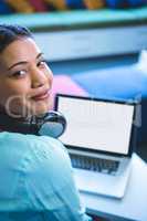 Portrait of smiling woman using laptop in library