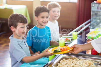 Woman serving food to smiling schoolchildren