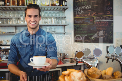 Portrait of happy owner offering coffee at cafeteria