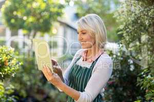 Gardener using digital tablet outside greenhouse