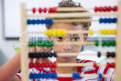 Boy playing with abacus in classroom