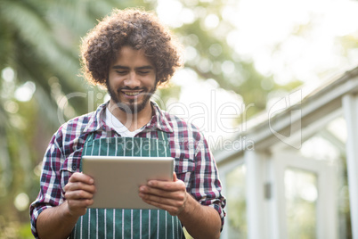 male gardener using tablet computer at greenhouse