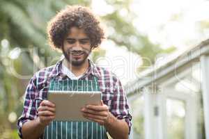 male gardener using tablet computer at greenhouse