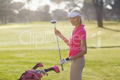 Portrait of cheerful mature woman carrying golf club