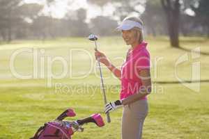 Portrait of cheerful mature woman carrying golf club