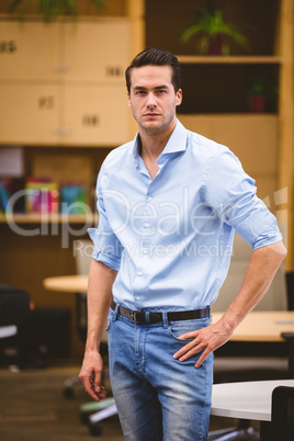 Smart businessman with hand on hip standing in meeting room
