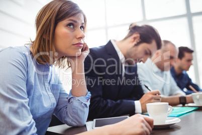 Thoughtful businesswoman with colleagues in meeting room