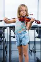 Portrait of girl playing violin in classroom