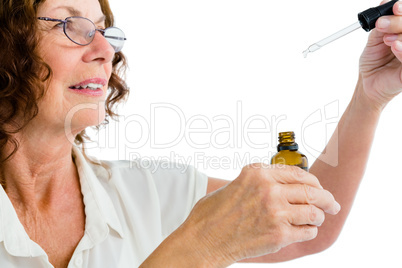 Close-up of mature woman holding dropper with medicine
