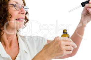 Close-up of mature woman holding dropper with medicine
