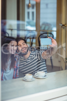 Cheerful couple taking selfie at cafe