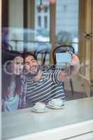 Cheerful couple taking selfie at cafe