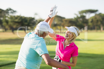 Cheerful golfer couple giving high five