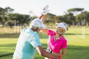 Cheerful golfer couple giving high five