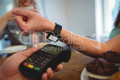 Cropped image of customer with smart watch at cafe