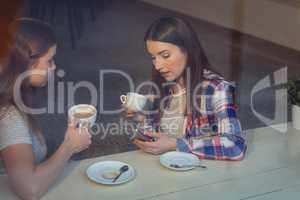 Beautiful woman using cellphone with friend at cafe