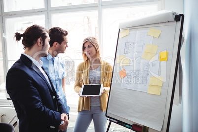 Businesswoman showing digital tablet to coworkers during meeting Businesswoman showing digital tablet to coworkers during meeting