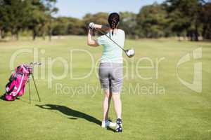 Full length rear view of golfer woman taking shot