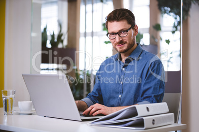 Portrait of confident businessman working on laptop at creative