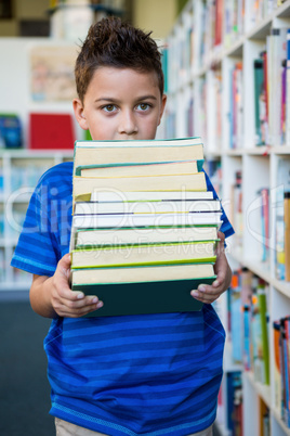 Boy holding books in school library