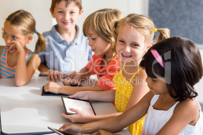 Smiling children using digital tablets