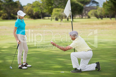 Mature man holding golf ball by woman