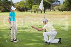 Mature man holding golf ball by woman