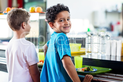 Schoolboy with classmate standing near canteen counter