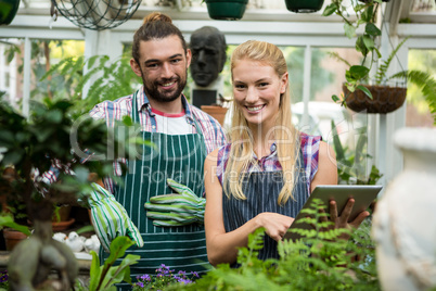 Portrait of happy colleagues with digital tablet at greenhouse