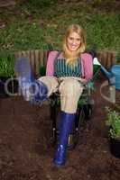 Portrait of happy gardener sitting in wheelbarrow at garden