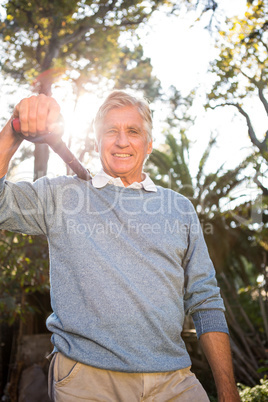 Portrait of happy gardener carrying shovel on shoulder at garden