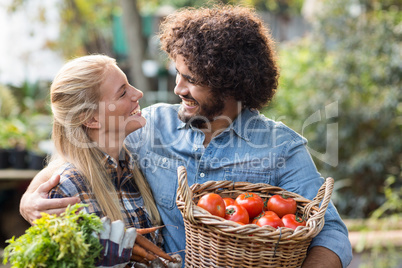 Couple carrying fresh vegetables outside greenhouse