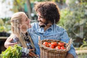Couple carrying fresh vegetables outside greenhouse