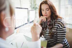 Businesswoman using laptop while discussing with colleague in cr