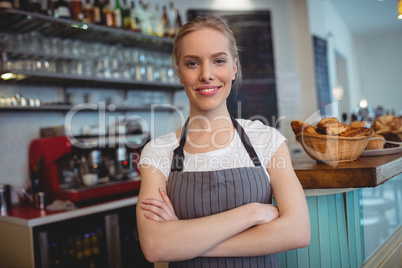 Portrait of happy waitress with arms crossed at cafe