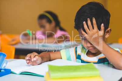 Irritated boy with head in hand looking at book