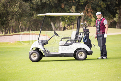 Golfer posing next to his golf buggy